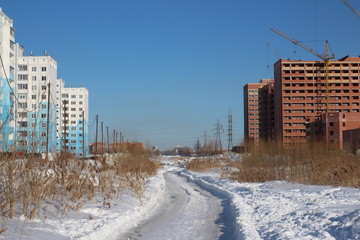 winter road between new buildings near multi storey houses under construction in the city of Chistaya Sloboda;