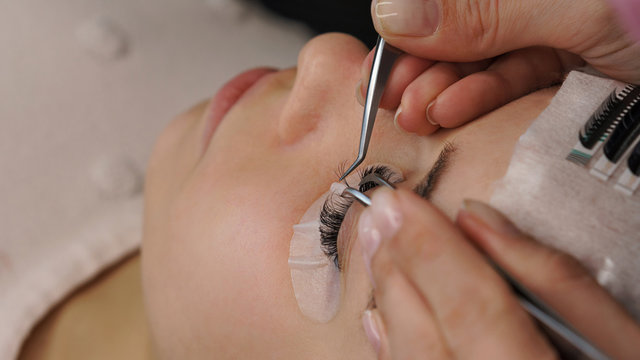 Eyelash extension procedure. Woman with long eyelashes in beauty salon. Lashes close up. Concept spa lash. Attention to details