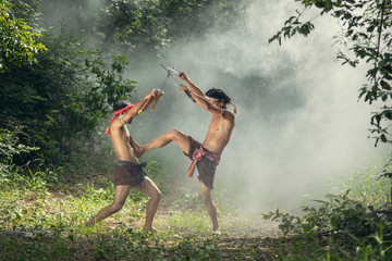 Thai legend warrior in action at forest,Ancient soldier holding swords ready to fight.