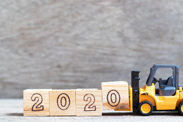 Toy forklift hold letter block 0 in word 2020 on wood background