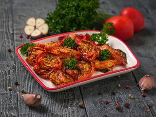 Dried tomatoes with garlic and parsley on a wooden table. Vegetarian food.