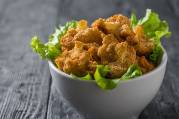 Cauliflower inflorescences baked with lettuce leaves in a white bowl.