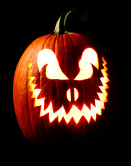 Halloween carved Jack o lantern pumpkin glowing eerily in the dark