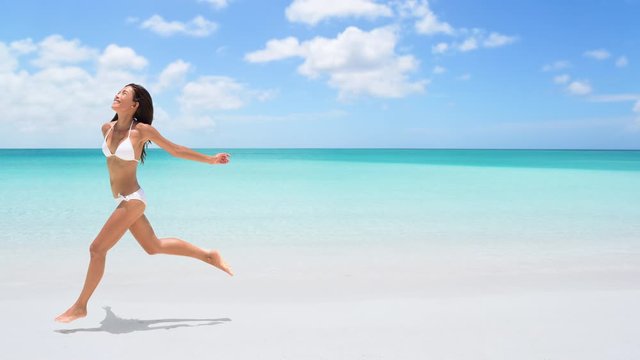 CINEMAGRAPH - seamless loop: Happy woman running on the beach on travel vacation holidays. Image full of aspiration and joy with Caucasian / Asian Chinese bikini model having fun. Looping Motion photo