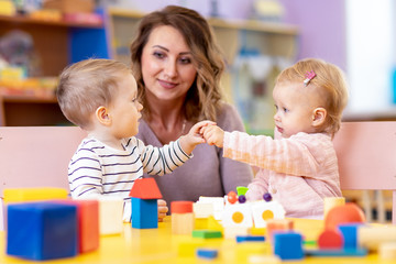 Little caucasian babies playing with Montessori toy in pre-school, creche or kindergarten