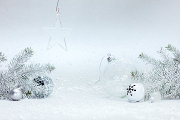 festive winter composition with christmas tree branches, various decorative balls and glass star on white snow background