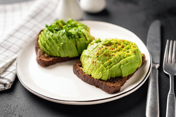Rye toast with cubed avocado garnished with spices served on a white plate. Healthy breakfast, lunch or snack. Closeup view, selective focus
