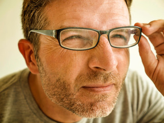 man checking vision trying glasses at optometrist during optical examination testing spectacles correcting myopia struggling suffering blurred eyesight problem