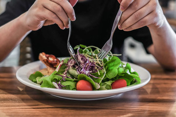 man eating healthy salad sitting on the table with green fresh ingredients indoors