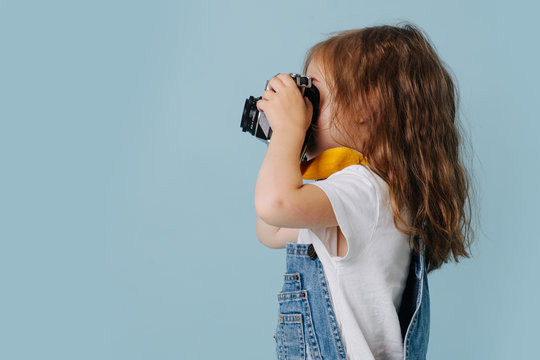 Toddler girl making photo with retro camera