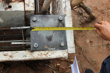 The technicians are using tape measure to measure the size of the steel plate used in the construction of the house