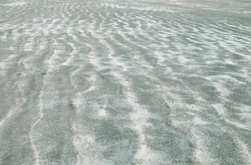 Waves of black sand on the beach