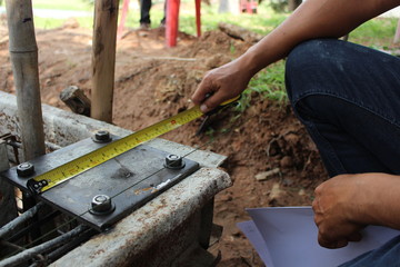 The technicians are using tape measure to measure the size of the steel plate used in the construction of the house