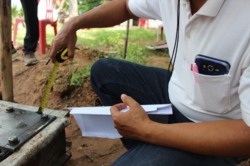 The technician is checking the size of the steel used in the construction of the base of the house. Take a blurred photo