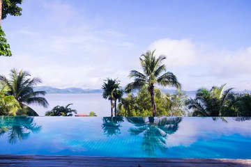 Fototapeta na wymiar Coconut trees reflex with swimming pool beside the beach