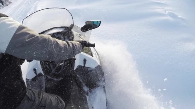 CLOSE UP: Snowmobile takes off and sprays snow into the camera. Sled riding race in back country. Snowmobile tracks spinning, kicking up fresh snow and spraying snowflakes. Snowmobiling