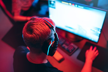 Professional gamer playing online games tournaments pc computer with headphones, Blurred red and...