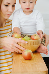 Fototapeta premium lly blond toddler boy is explores, plays with apples from backet.