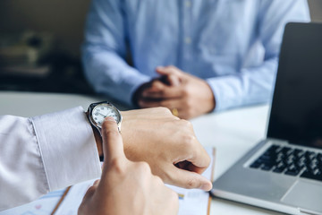 Close up view of businessman pointing on hand wristwatch  at meeting, showing unpunctual partner he...