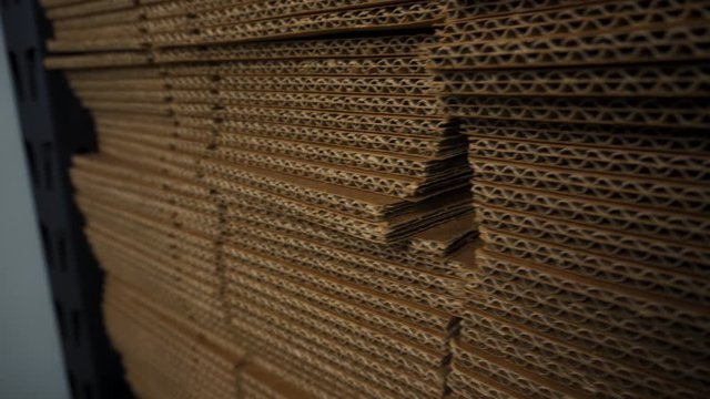 Pan right to left of big stack of flat cardboard boxes