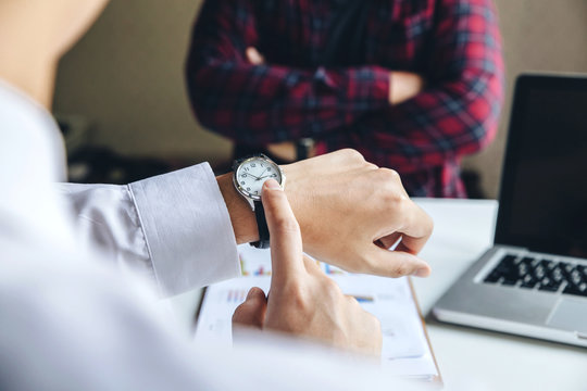 Close up view of businessman pointing on hand wristwatch at meeting, showing unpunctual partner he is being late