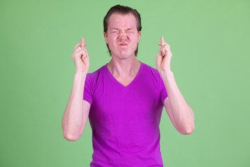 Fototapeta premium Portrait of young handsome man wishing with fingers crossed
