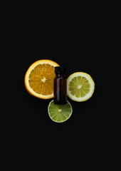 sliced oranges, lemons, and limes with essential oil bottle, amber bottle for aromatherapy oil, citrus rounds group lines on dark background, copy space, copyspace