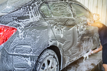 Car washing, workers are using foam to clean gray cars to foam all over the car. Before using high-pressure water to wash off