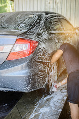 Car washing, workers are using foam to clean gray cars to foam all over the car. Before using high-pressure water to wash off
