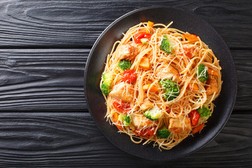 Tasty pasta with chicken and vegetables close-up on a plate. Horizontal top view