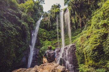 Man in turquoise dress at the Sekumpul waterfalls in jungles on Bali island, Indonesia. Bali Travel Concept