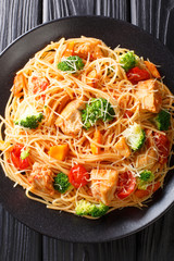 Italian pasta with broccoli, chicken, tomatoes and pumpkin close-up on a plate. Vertical top view