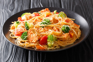 Spaghetti recipe with chicken, cheese and vegetables in tomato sauce close-up on a plate. horizontal