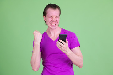 Portrait of happy young man using phone and getting good news