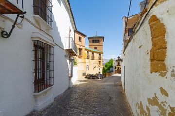 Fototapeta premium A small narrow street with white houses and abundant greenery in the old European city