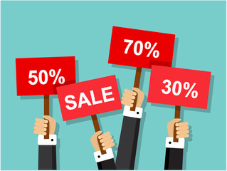 hands holding red signs with discounts and sales