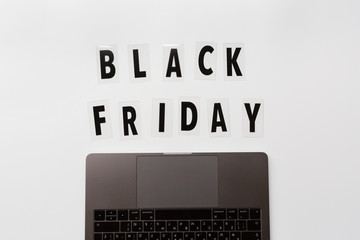 Creative promotion composition Black friday text and laptop on white background. Flat lay, top view, overhead, mockup, template. Minimal abstract background. Online shopping, sale, promo. Web banner