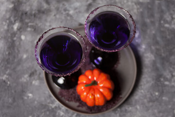 Two glasses with purple cocktail, pumpkin for Halloween party on the dark background