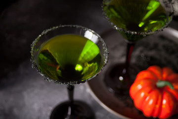Two glasses with green zombie cocktail for Halloween party on the gray background
