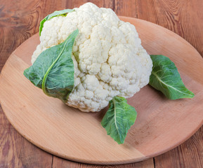 Fresh cauliflower head on the wooden serving board