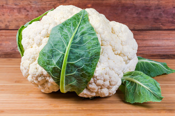 Head of freshly harvested cauliflower on a wooden surface