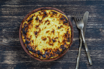 Sweet cottage cheese casserole with raisins and semolina on wooden table. Ceramic bowl with baked cottage cheese casserole , closeup, top view