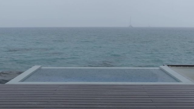 LOOP VIDEO: Rain on Vacation - video of luxury pool while raining and bad weather on holidays getaway travel. Seamless Looping video.