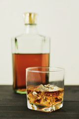 glass of whiskey with ice cubes on wooden table