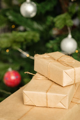 Gift boxs wrapped in recycled paper with bow. Merry Christmas and Happy Holidays! Christmas gift box against bokeh background. 