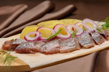 Sliced herring with onions on the wooden doard.