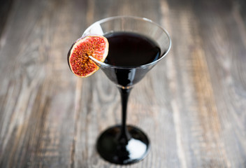 Martini cocktail with black vodka and figs on the rustic background. Selective focus. Shallow depth of field.