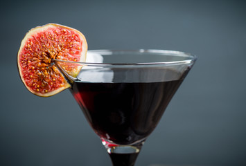 Martini cocktail with black vodka and figs on the rustic background. Selective focus. Shallow depth of field.
