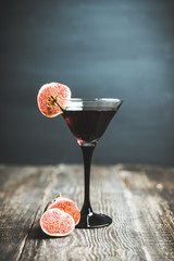 Martini cocktail with black vodka and figs on the rustic background. Selective focus. Shallow depth...