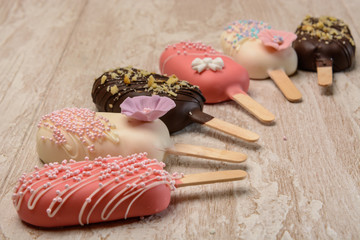 A few cakes in the form of ice cream is on a wooden table, forming a semicircle.